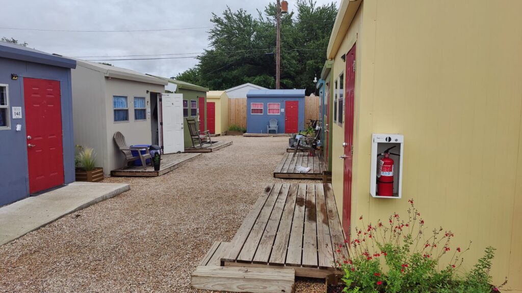 Colorful tiny homes painted blue, beige, green, and yellow with small wooden decks