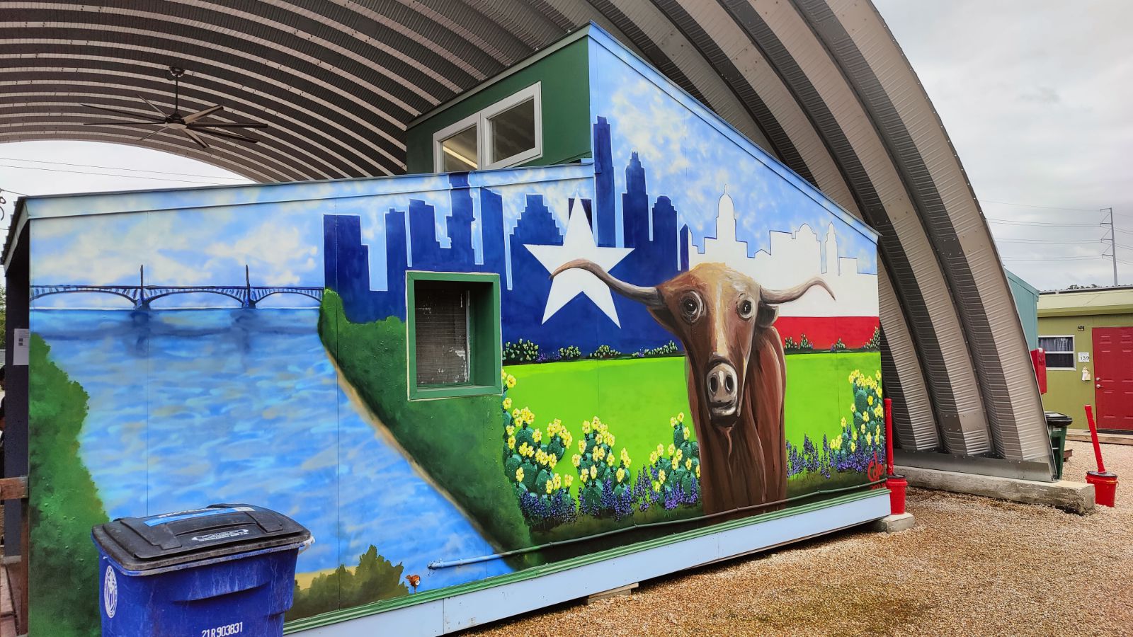 Mural showing longhorn on green lawn with Austin skyline painted like Texas flag