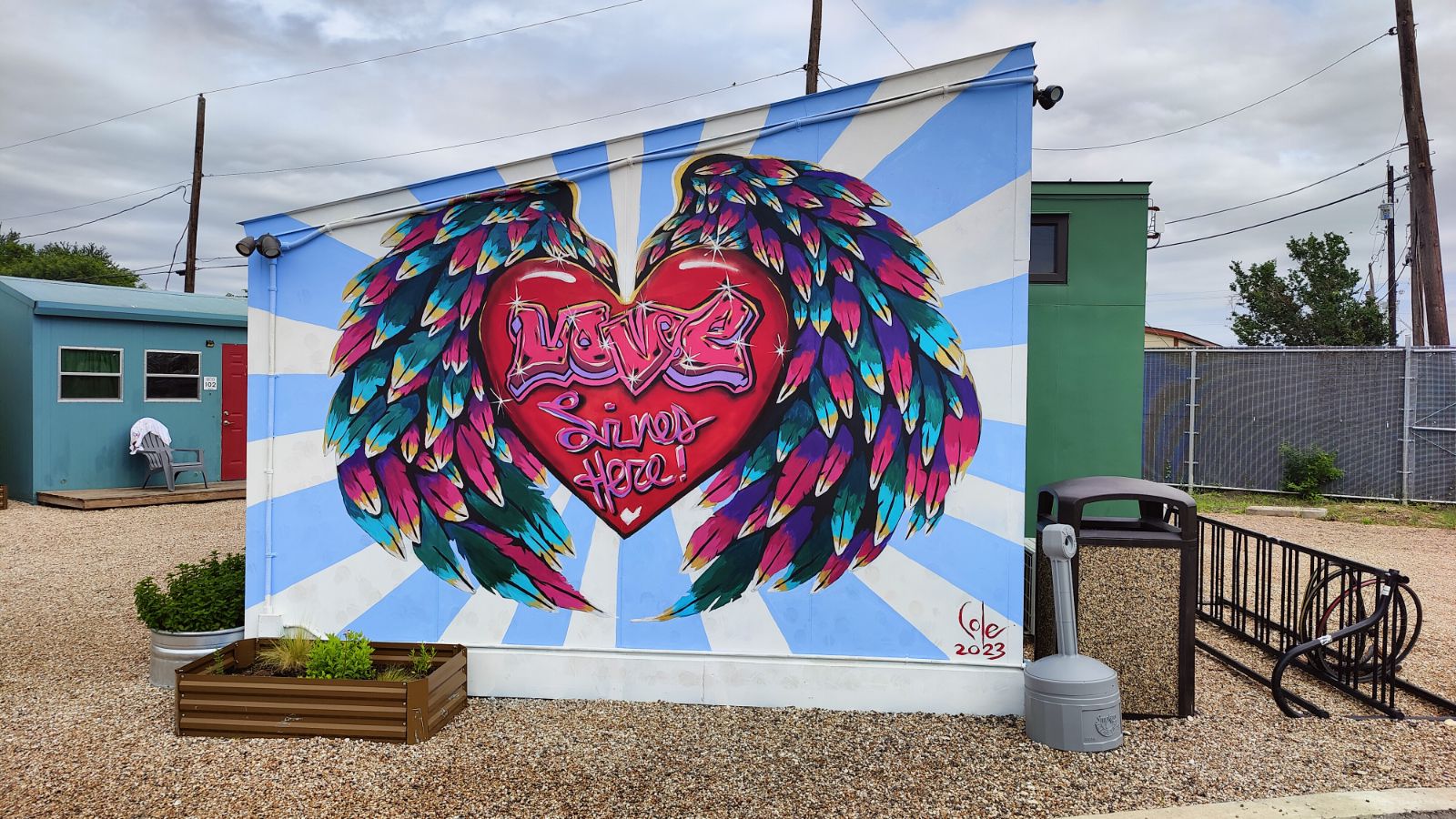 Mural of heart with wings and text that says "love lives here"